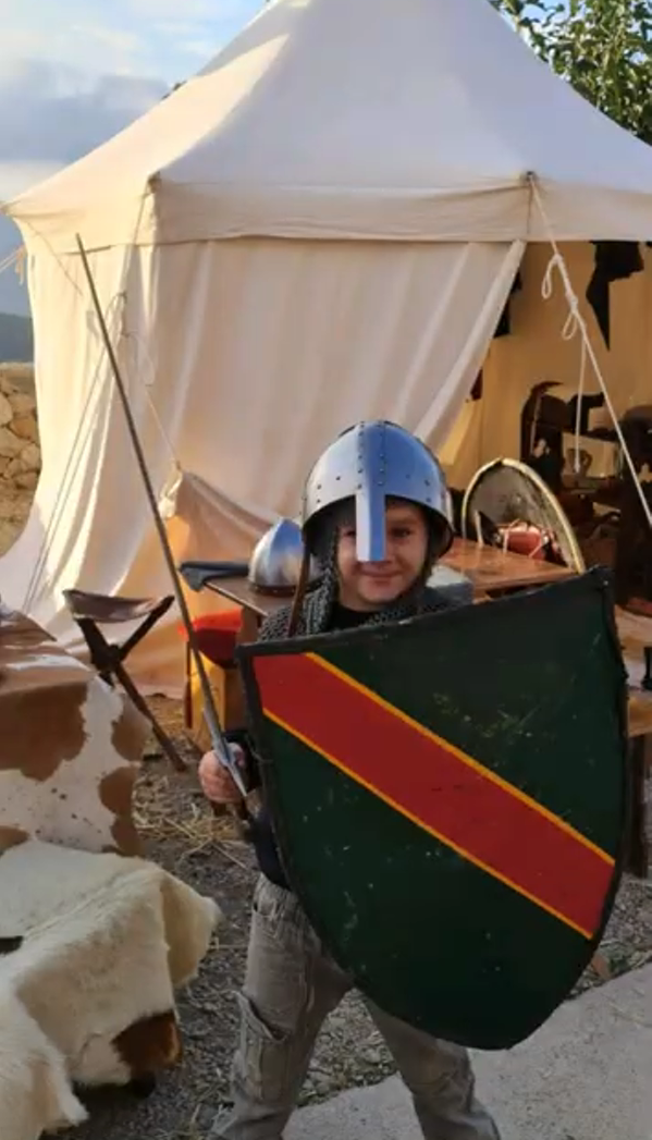 Un niño con casco y escudo en el campamento medieval de Culla
